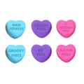 Color Change Squeeze Heart S3 - Six heart-shaped sensory toys arranged in two rows. The top row has blue, purple, and pink hearts labeled "MAIN SQUEEZE", "SQUISHY 4 LIFE", and "I YOU". The bottom row has blue, purple, and pink hearts labeled "GROOVY VIBES", "BE YOU", and "ALL THE FEELS".