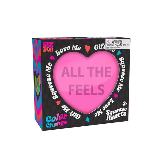 A boxed Color Change Squeeze Heart S3 toy. The packaging is predominantly black with colorful accents, featuring phrases like "ALL THE FEELS," "Squeeze Me," "Love Me," and "Gift Me." The box also includes a choking hazard warning for small parts.