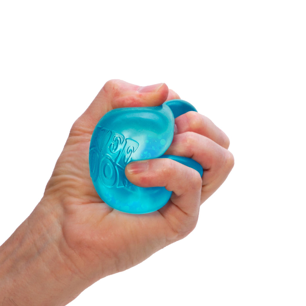 Dream Drop V2 - A hand is squeezing a blue sensory toy against a white background. The toy has some texture and appears slightly translucent. The fingers are wrapped tightly around it, indicating a firm grip.